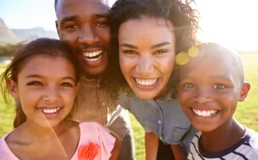laughing-black-family-outdoors-close-up-back-lit-PPCMZD4.jpg